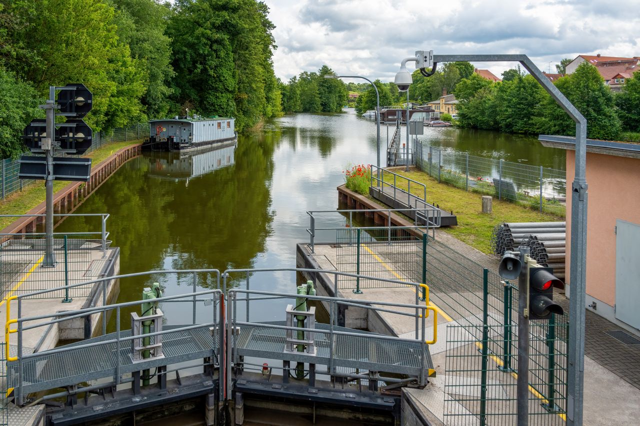 about-02 Tranquil canal lock with lush trees and calm waters, perfect for a serene boat trip.